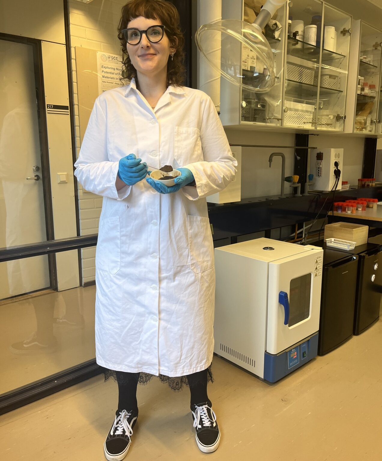 Jaana Ailus holding a sample of the microbial extract in her laboratory